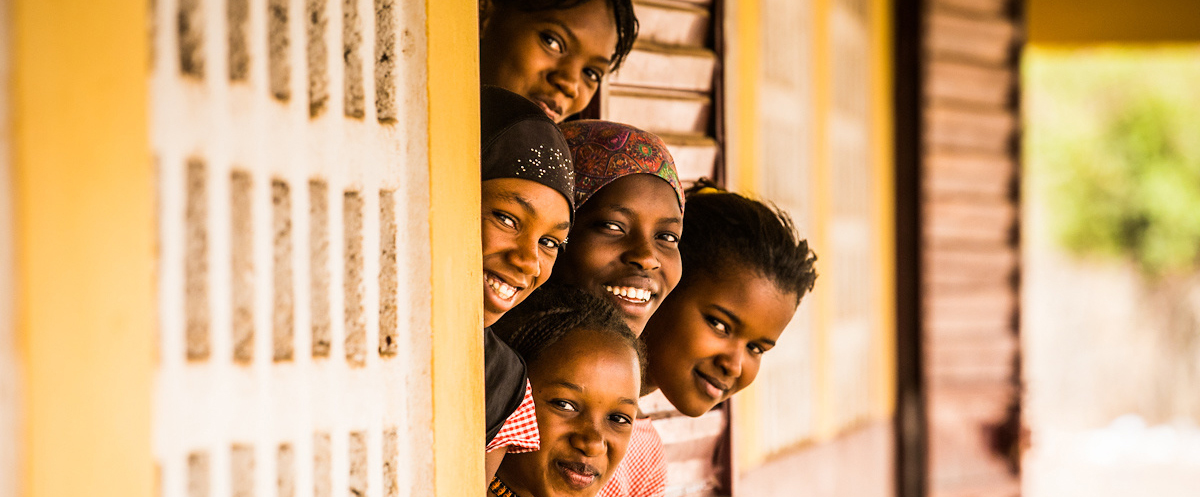 Adolescent girls smiling at doorway in Guinea